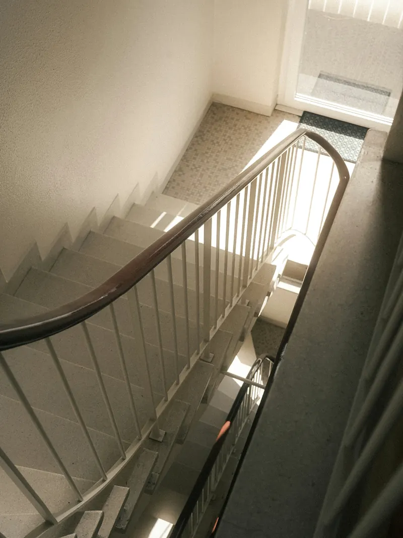 Sauberes, helles Treppenhaus mit Holzhandlauf von oben